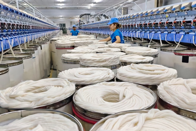 Employees work on the spinning production line at a workshop of a textile factory.
